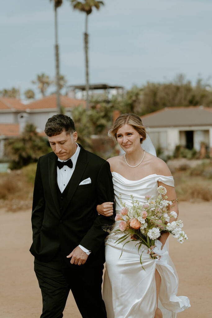 bride walking down the aisle at beach wedding at sunset cliffs