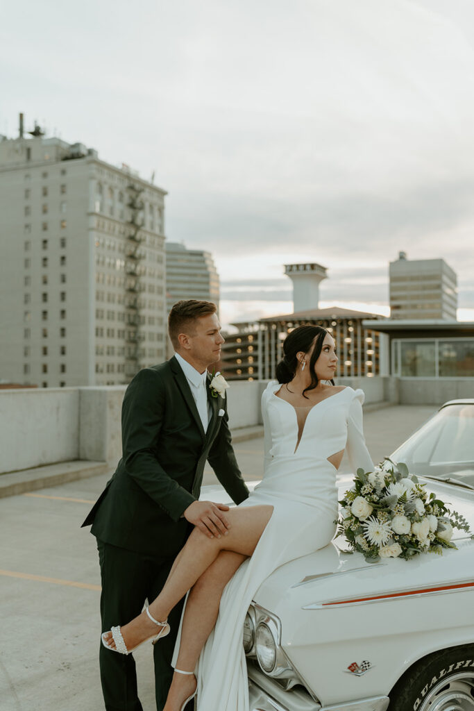 bride and groom with classic car on the rooftop after downtown elopement ceremony