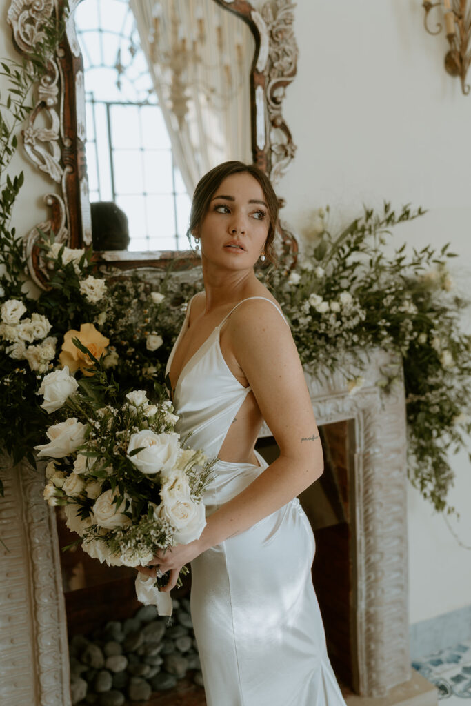 The bride in a silky wedding gown, standing amidst lemon-inspired decor.