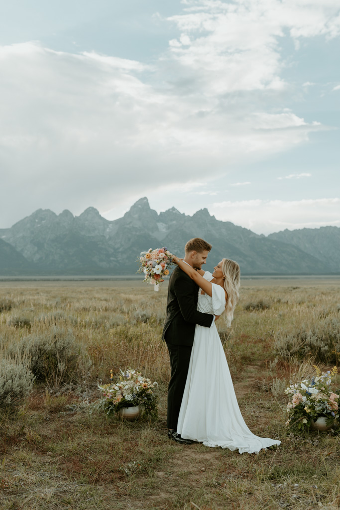 bride and groom stand in a field with passing thunderstorm clouds above