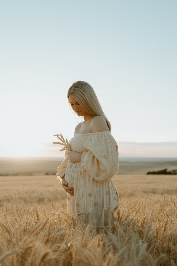 Haley wearing a flowing dress, her baby bump beautifully showcased amidst the golden wheat.