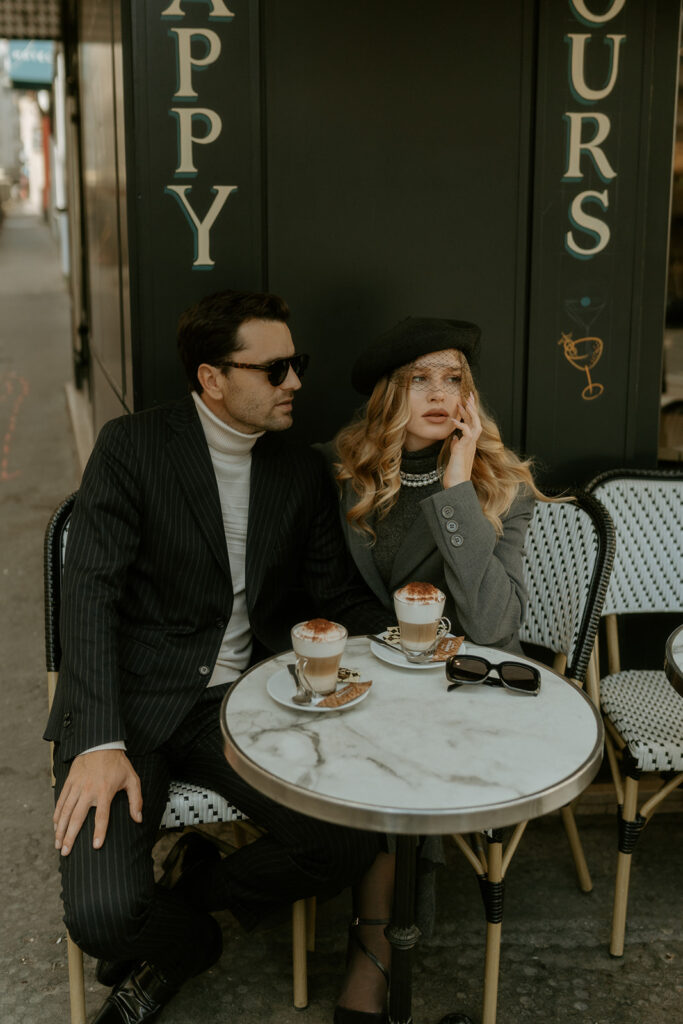 A couple sits at a charming Parisian cafe, enjoying coffee and each other's company against the backdrop of a quaint street scene.