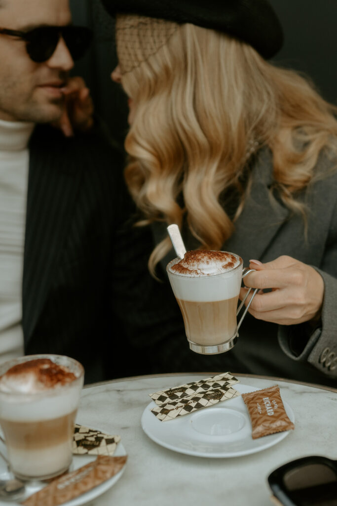 A couple sits at a charming Parisian cafe, enjoying coffee and each other's company against the backdrop of a quaint street scene.