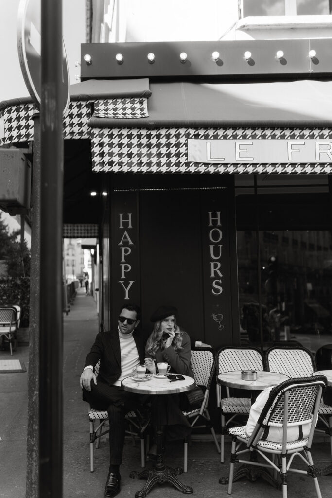 A couple sits at a charming Parisian cafe, enjoying coffee and each other's company against the backdrop of a quaint street scene.