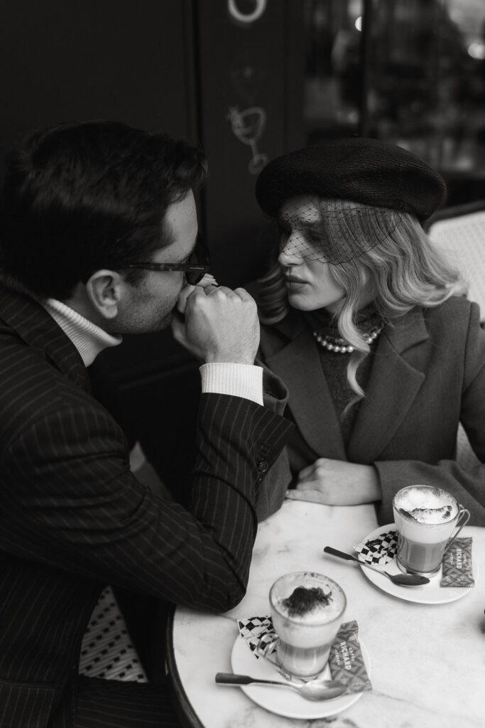 A couple sits at a charming Parisian cafe, enjoying coffee and each other's company against the backdrop of a quaint street scene.