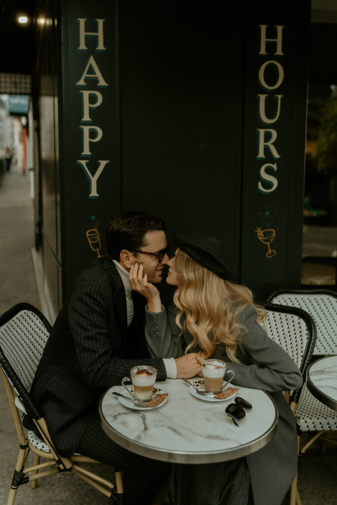 A couple sits at a charming Parisian cafe, enjoying coffee and each other's company against the backdrop of a quaint street scene.